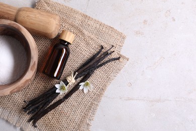 Photo of Vanilla pods, essential oil, flowers and sugar in bowl on light gray table, flat lay. Space for text