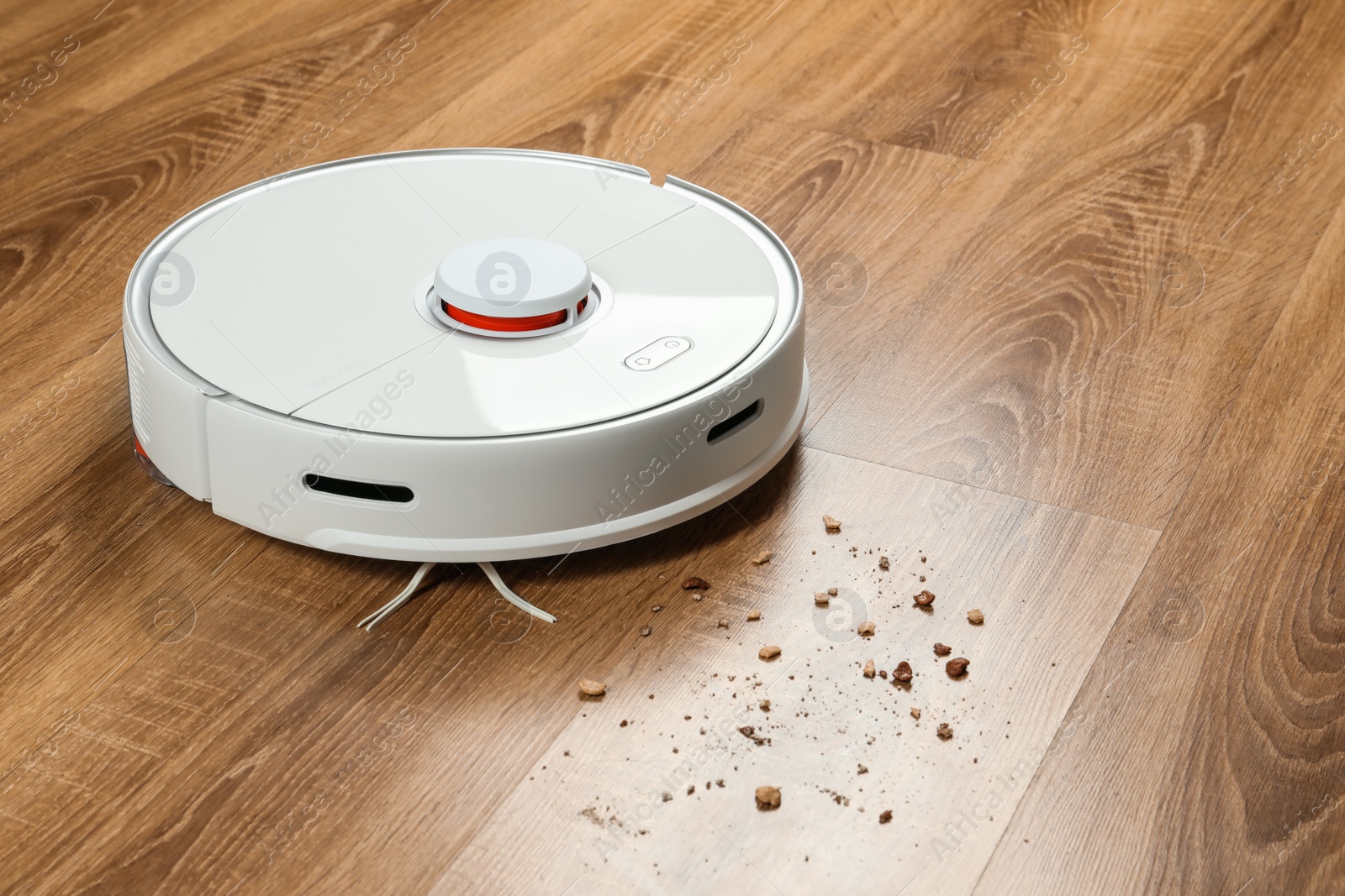 Photo of Robotic vacuum cleaner removing dirt from wooden floor indoors, space for text