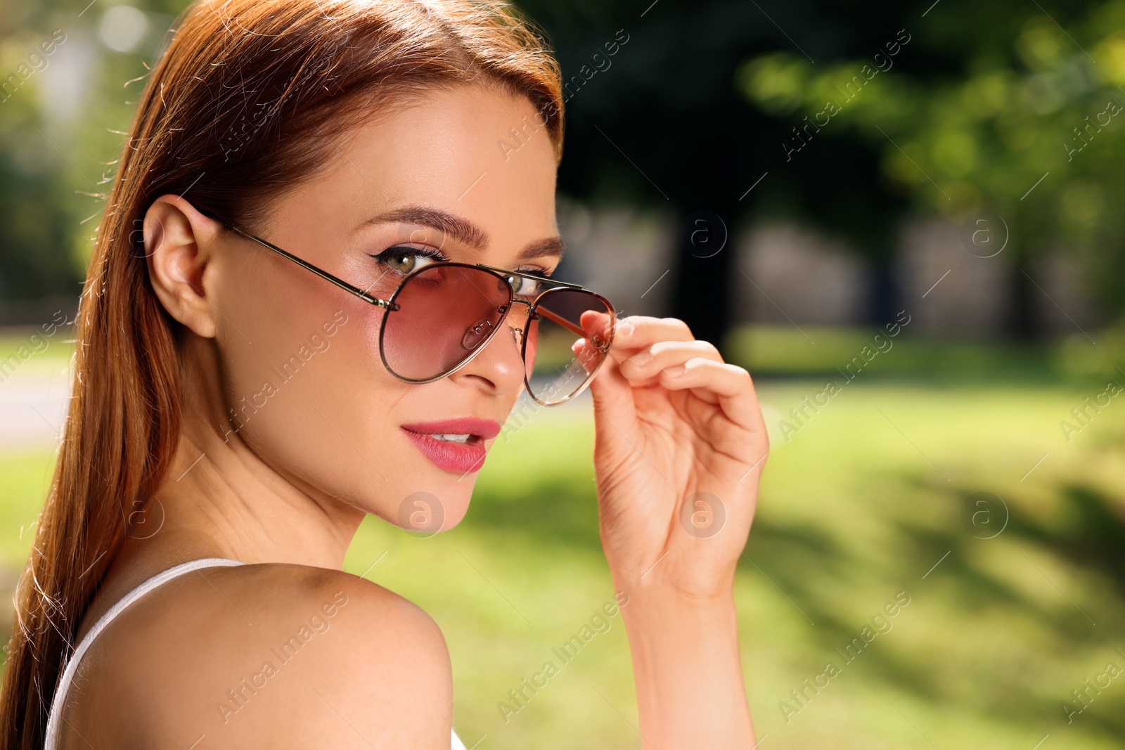 Photo of Beautiful woman wearing sunglasses in park, space for text