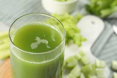 Photo of Glass of delicious celery juice and vegetables on wooden board, closeup. Space for text