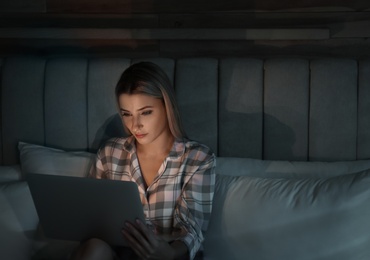 Young woman using laptop in bed at night. Sleeping disorder problem