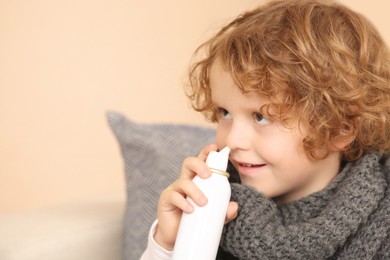 Photo of Cute little boy using nasal spray indoors. Effective medicine