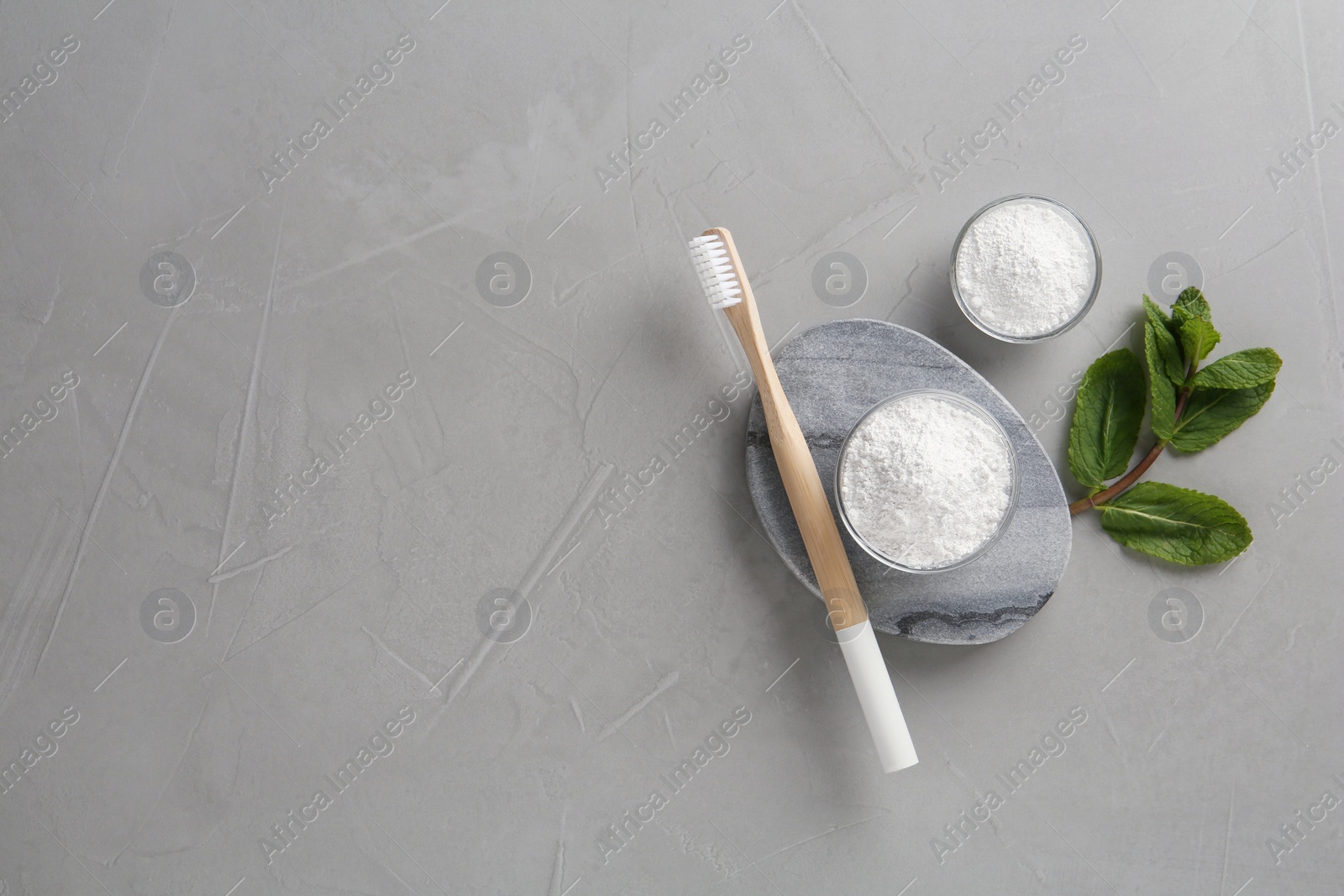 Photo of Tooth powder, brush and mint on grey table, flat lay. Space for text