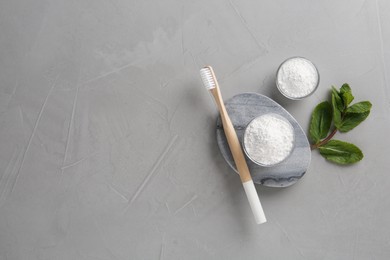 Tooth powder, brush and mint on grey table, flat lay. Space for text