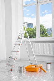 Photo of Stepladder and painting tools near window in empty room