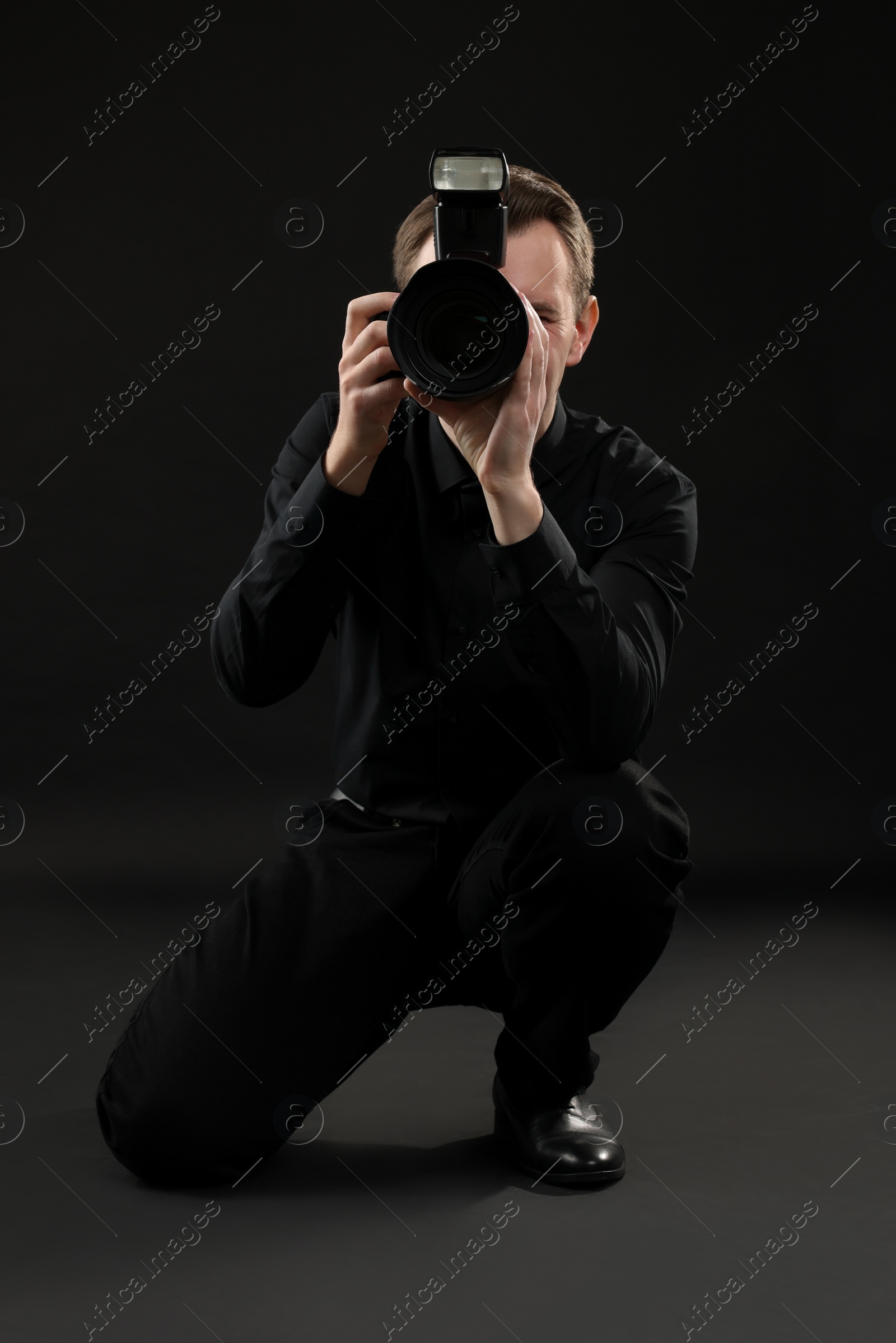 Photo of Professional photographer taking picture on black background