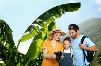 Family with child in mountains. Mother showing photo on camera