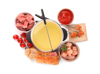 Photo of Fondue pot with oil, forks, meat pieces and other products isolated on white, top view