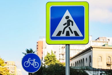 Different road signs against blue sky on city street