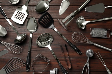 Photo of Set of modern cooking utensils on brown wooden table, flat lay