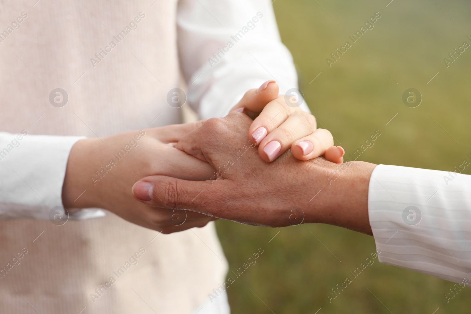 Photo of Trust and support. Women joining hands outdoors, closeup