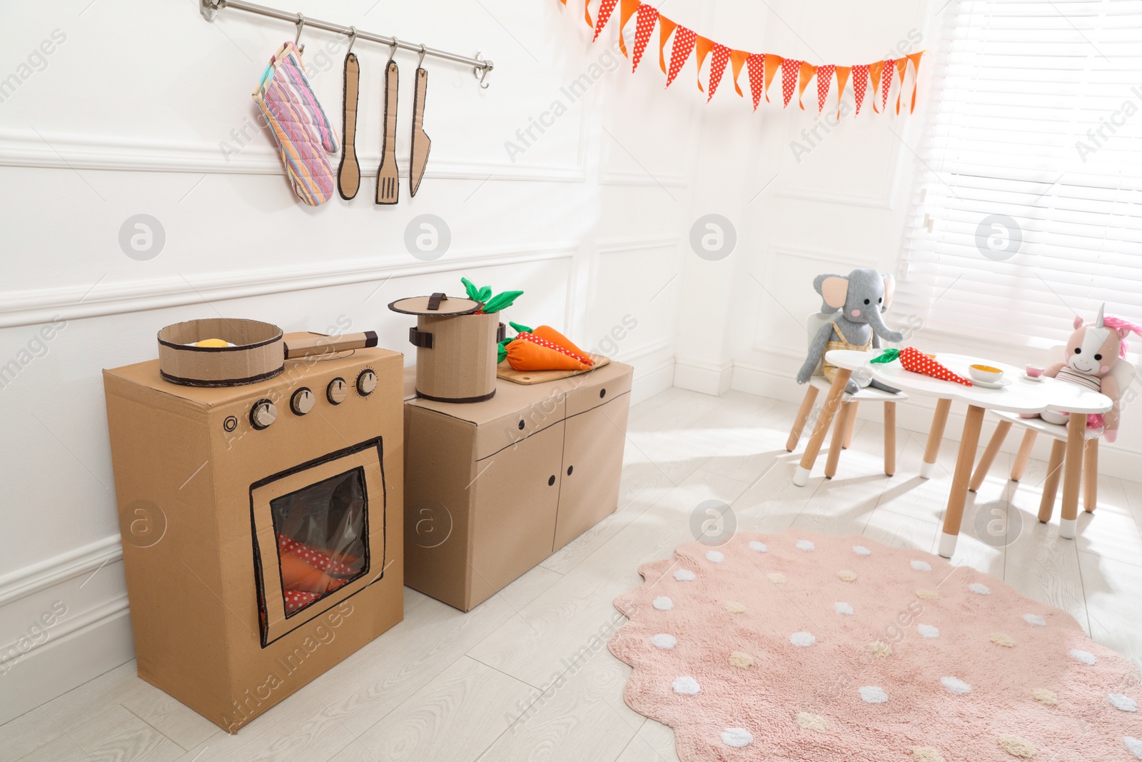 Photo of Toy cardboard kitchen with stove and utensils at home