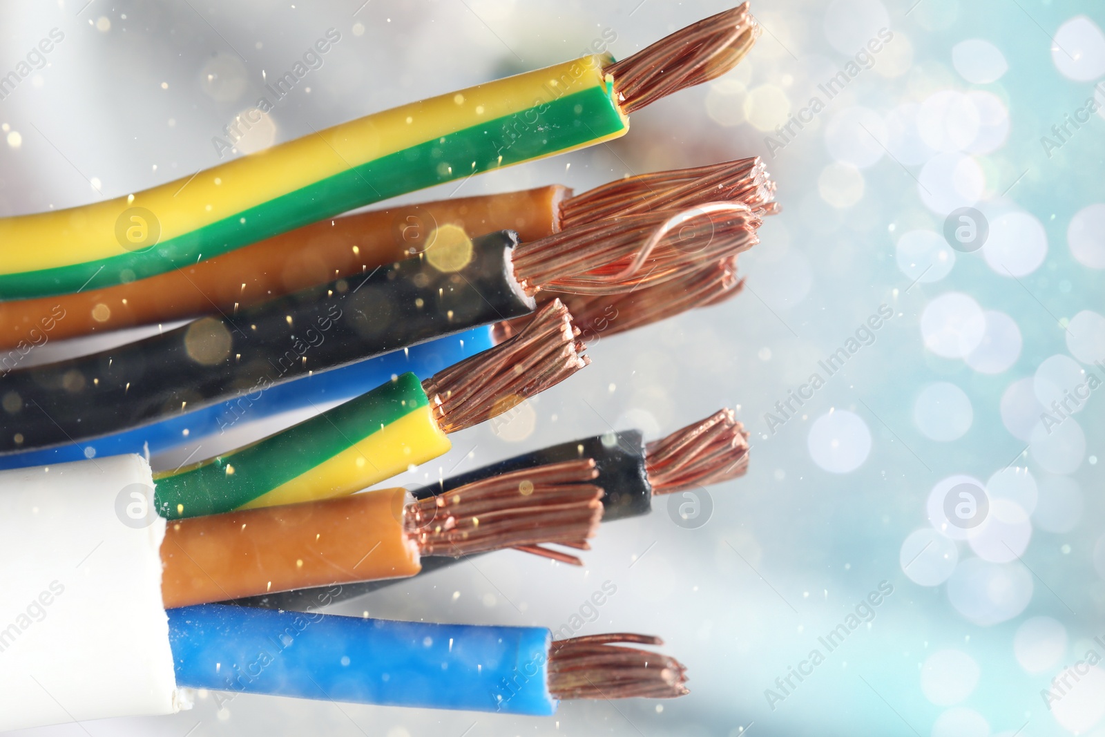 Image of Colorful electrical wires against background with blurred lights, closeup. Space for text