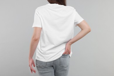 Photo of Woman in white t-shirt on grey background, back view