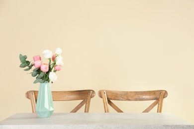 Vase with beautiful flowers as element of interior design on table in room. Space for text