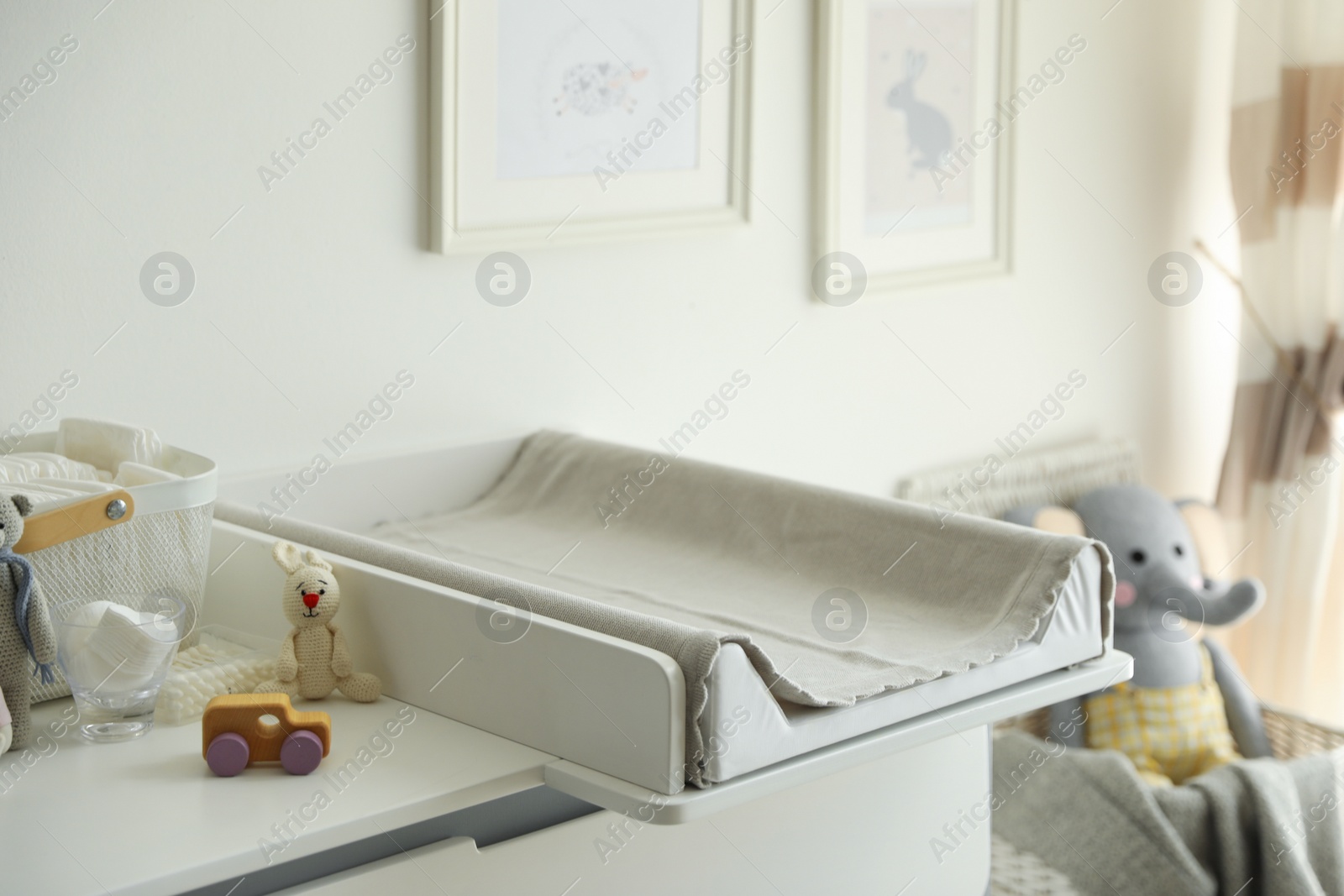 Photo of Modern changing table with toys and accessories in baby room