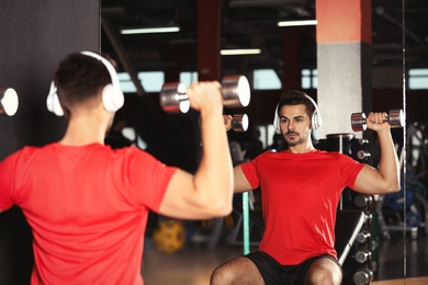 Photo of Young man with headphones listening to music and working out at gym