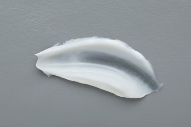Photo of Body cream sample on grey background, closeup. Cosmetic product