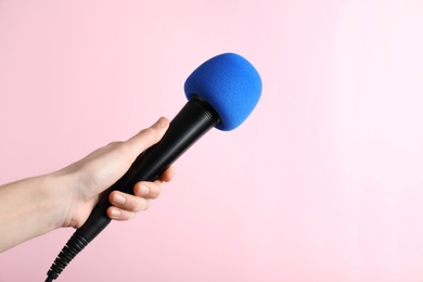 Woman holding microphone on color background, space for text