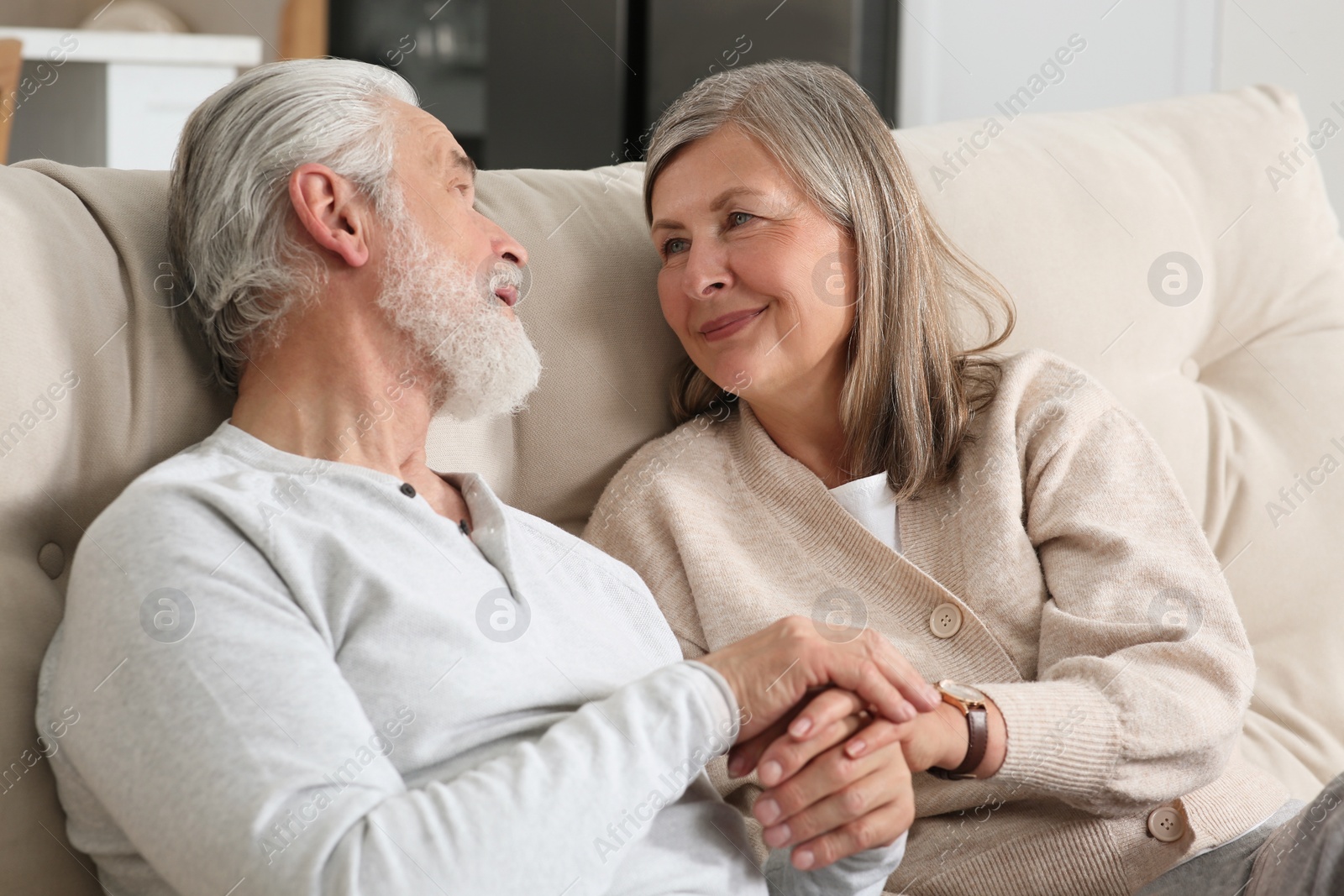 Photo of Affectionate senior couple relaxing on sofa at home