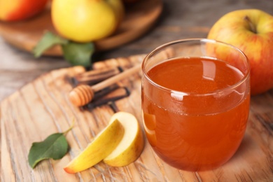 Photo of Glass of honey and apples on wooden board