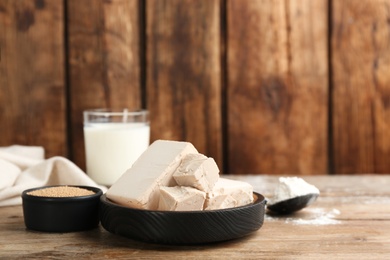 Photo of Compressed and granulated yeast on wooden table. Space for text