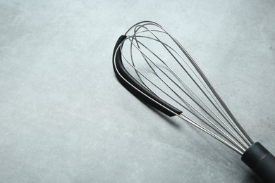 Metal whisk on gray table, space for text