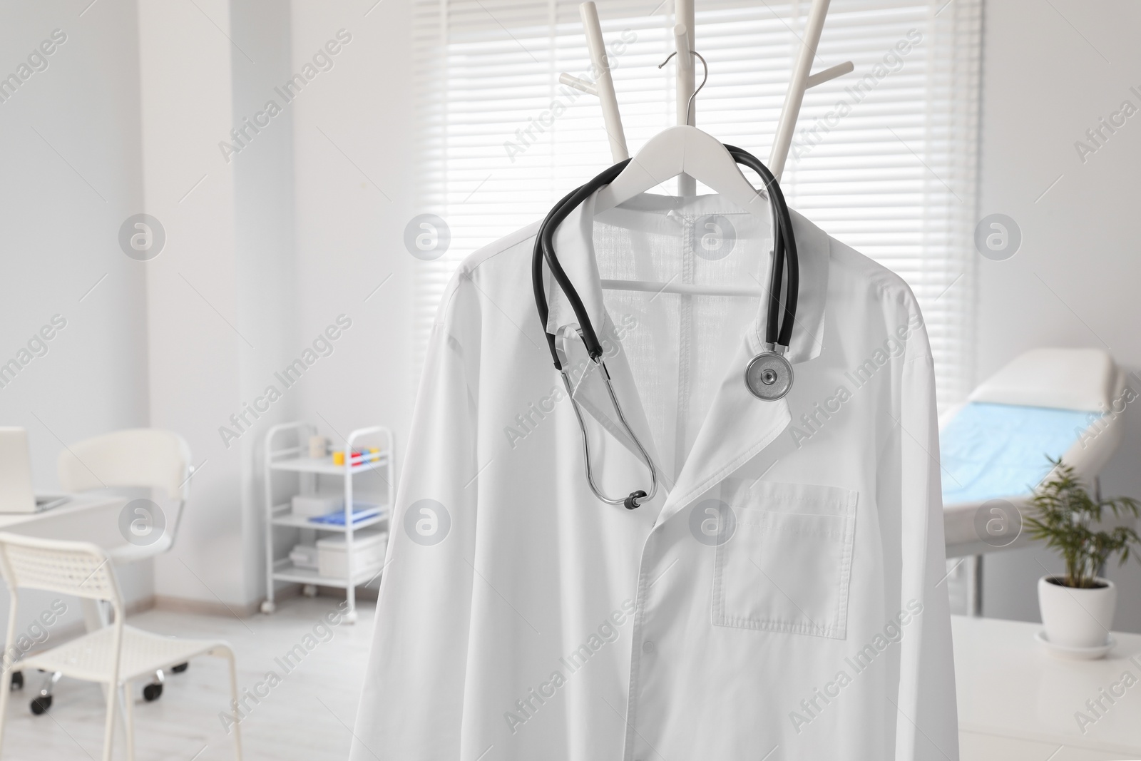 Photo of White doctor's gown and stethoscope on rack in clinic