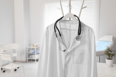 Photo of White doctor's gown and stethoscope on rack in clinic