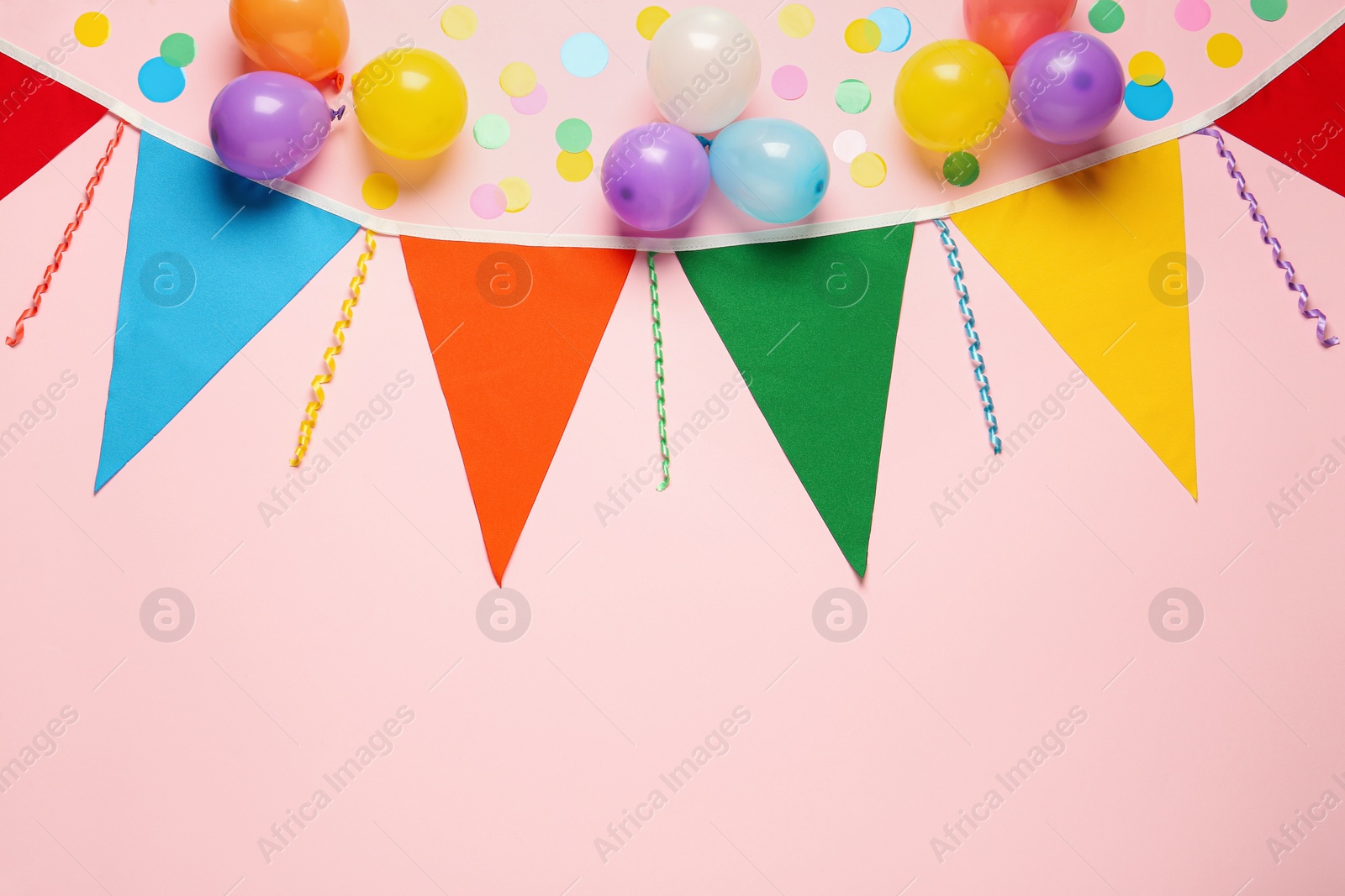 Photo of Bunting with colorful triangular flags and other festive decor on pink background, flat lay. Space for text