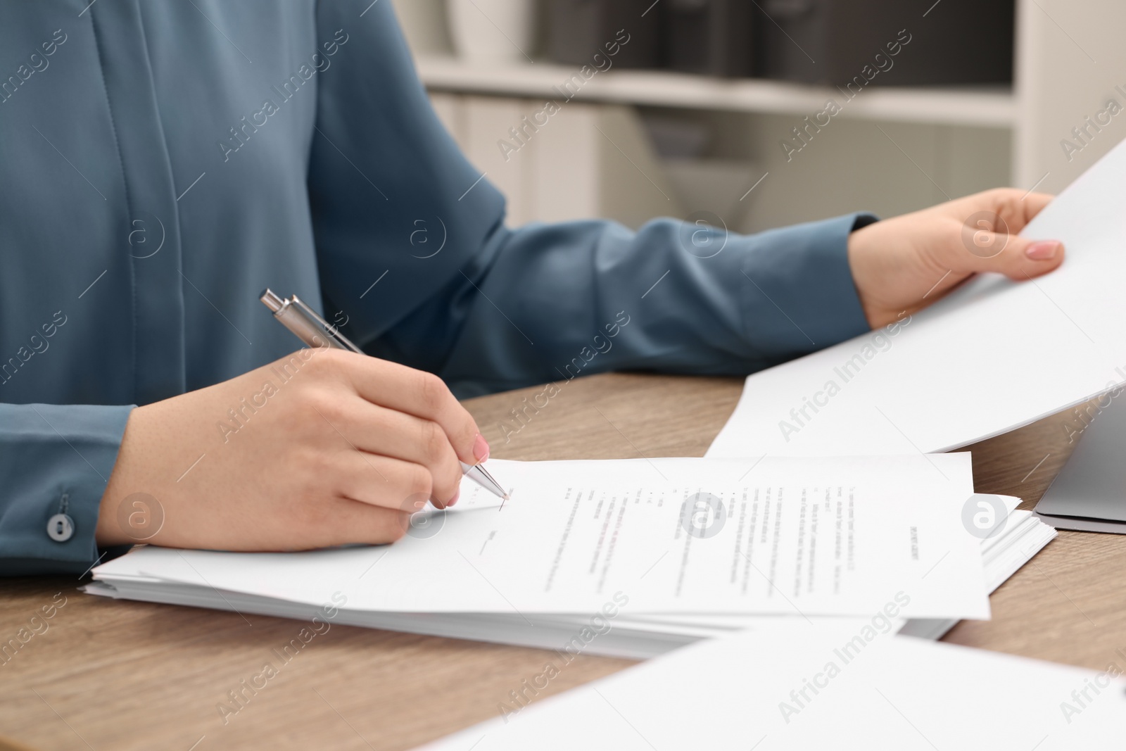 Photo of Woman signing document at wooden table, closeup