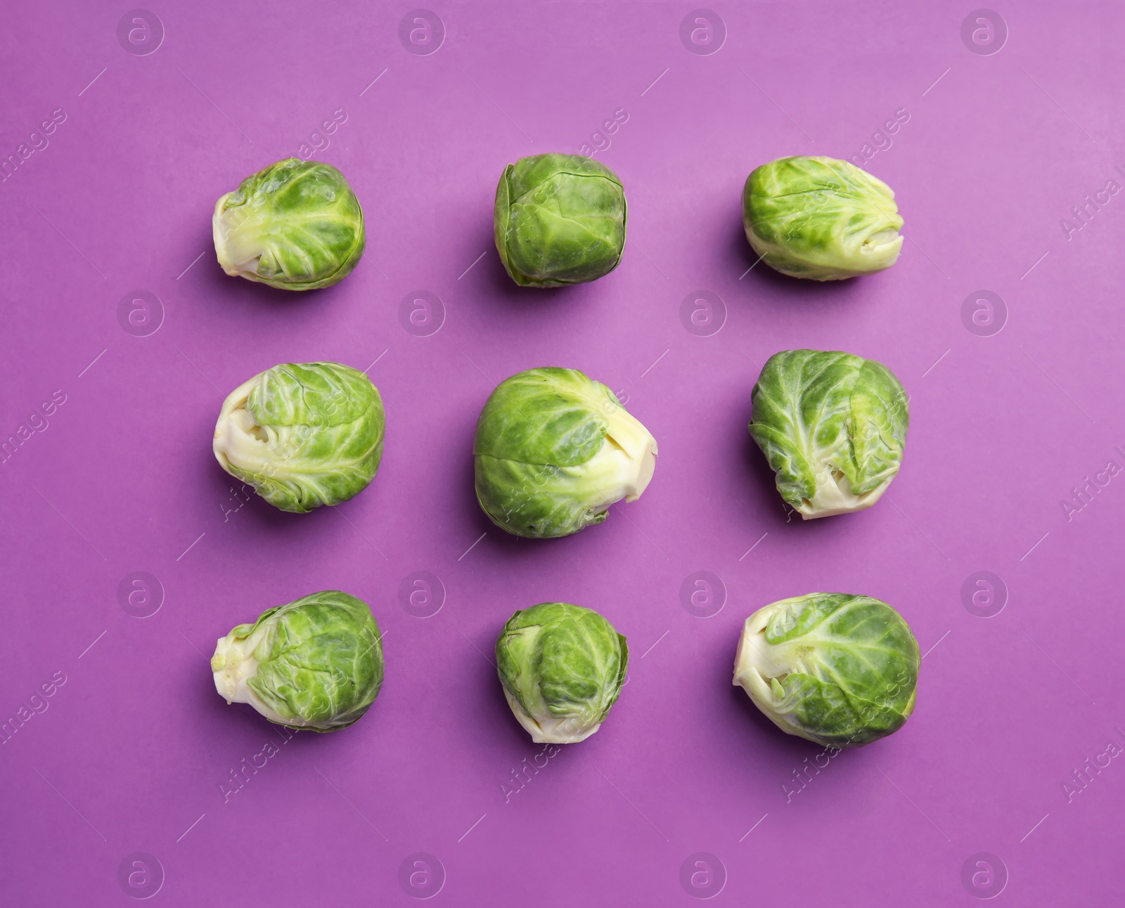 Photo of Fresh Brussels sprouts on purple background, flat lay