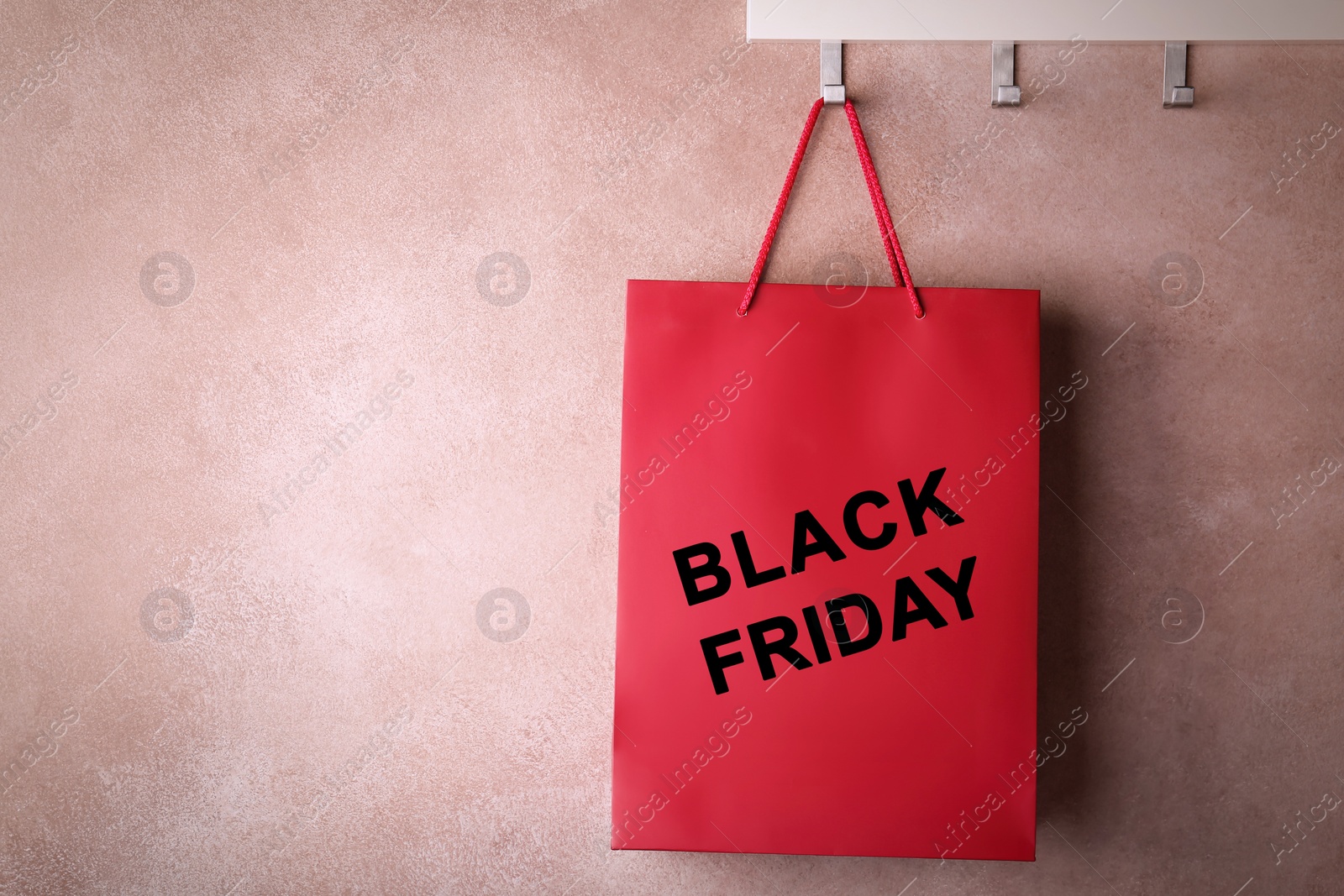 Image of Paper shopping bag with phrase BLACK FRIDAY on rack near color wall, space for text