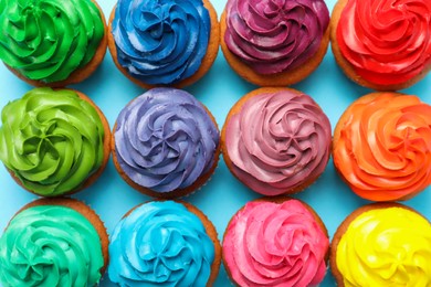 Photo of Many delicious colorful cupcakes on light blue background, flat lay