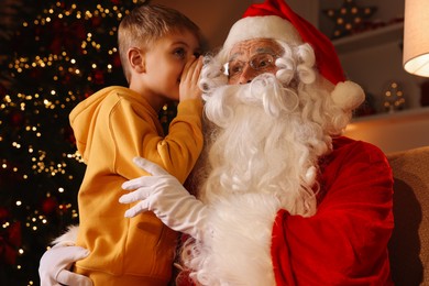 Little boy whispering his wish to Santa near Christmas tree in room