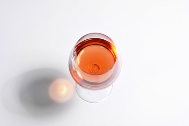 Glass of rose wine on white background, above view