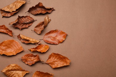 Photo of Dry autumn leaves on brown background, flat lay. Space for text