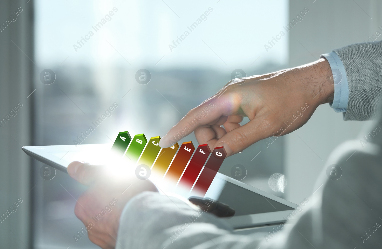 Image of Energy efficiency rating coming out of tablet. Man using device indoors, closeup