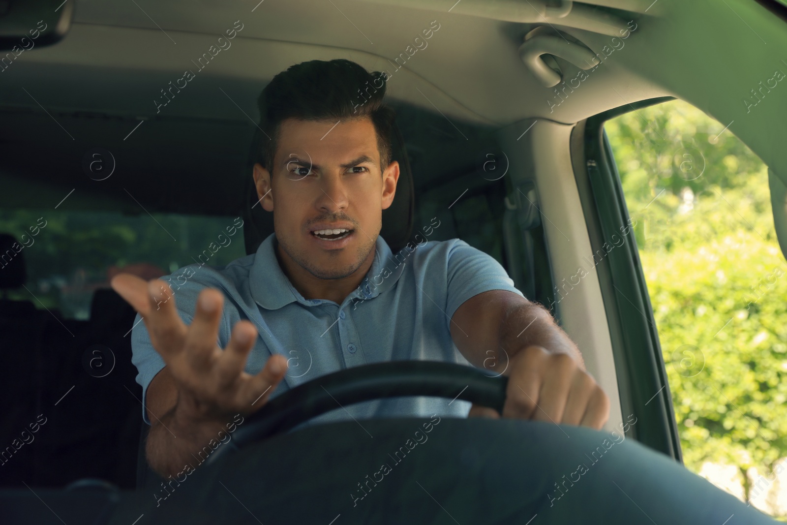 Photo of Stressed angry man in driver's seat of modern car, view through windshield