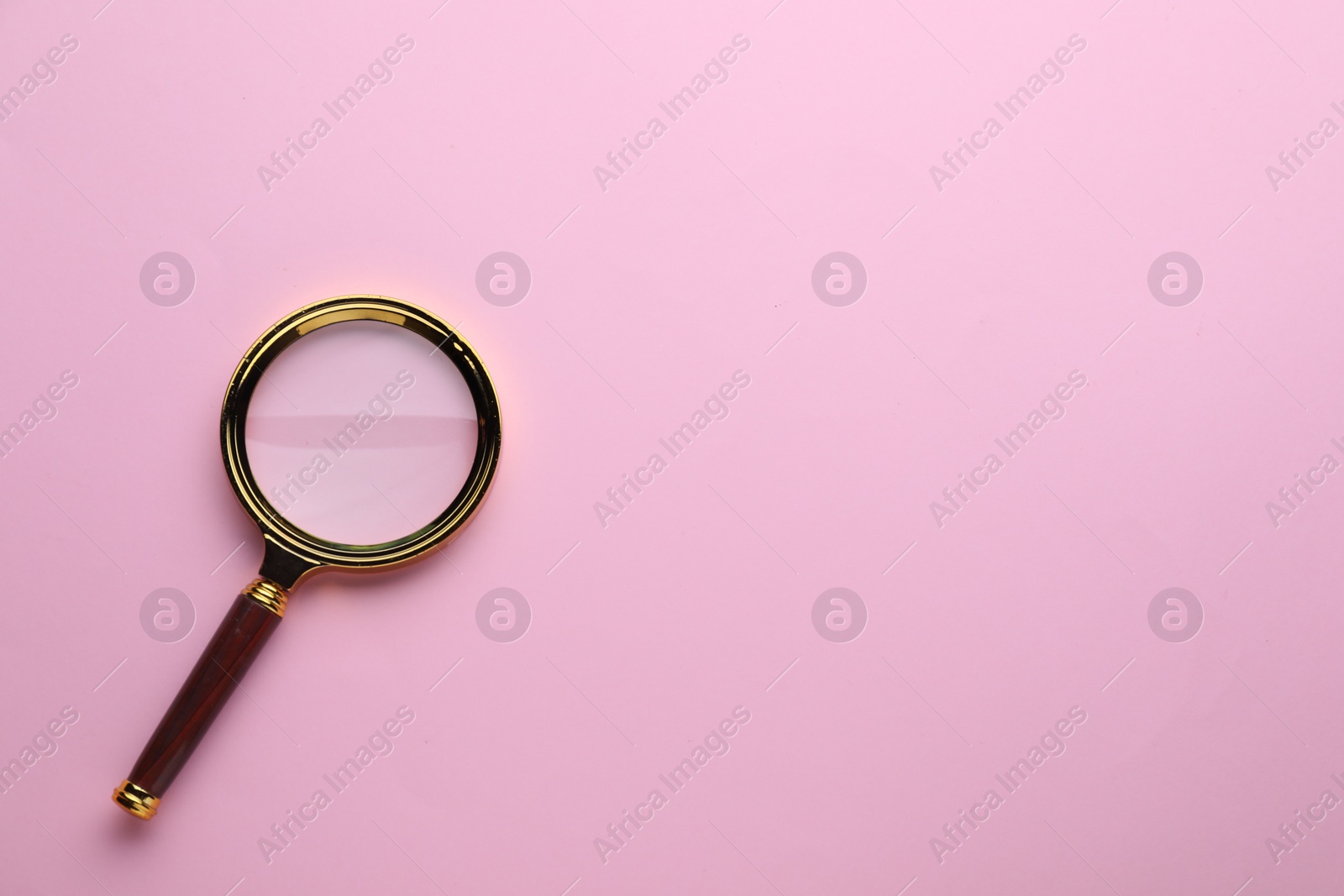 Photo of Magnifying glass on pink background, top view. Space for text