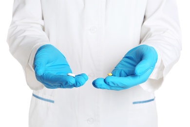 Doctor in medical gloves holding pills on white background