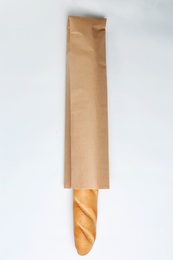 Photo of Paper bag with baguette on white background, top view. Space for design