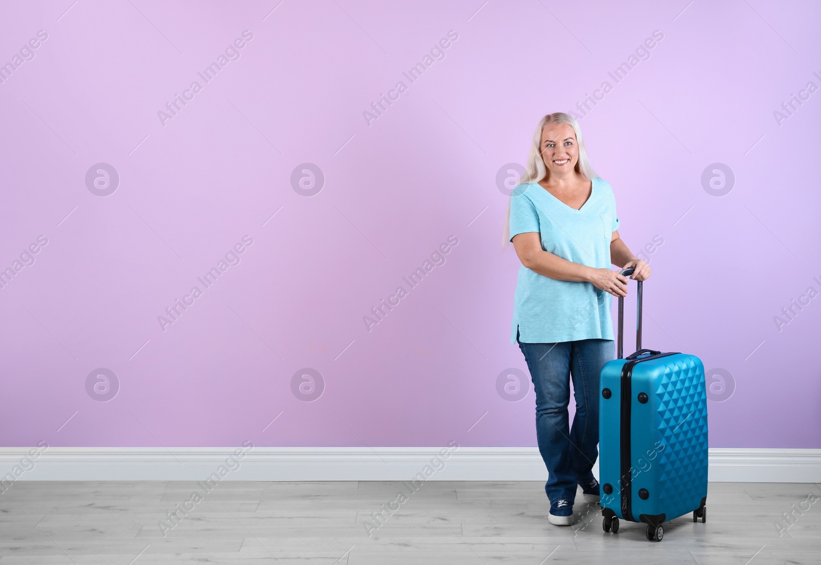 Photo of Senior woman with suitcase near color wall. Space for text
