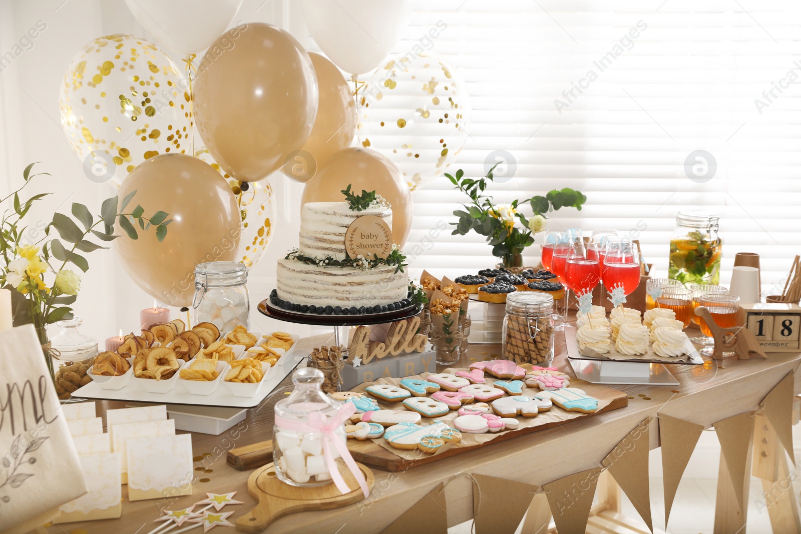 Photo of Baby shower party. Different delicious treats on wooden table and decor indoors