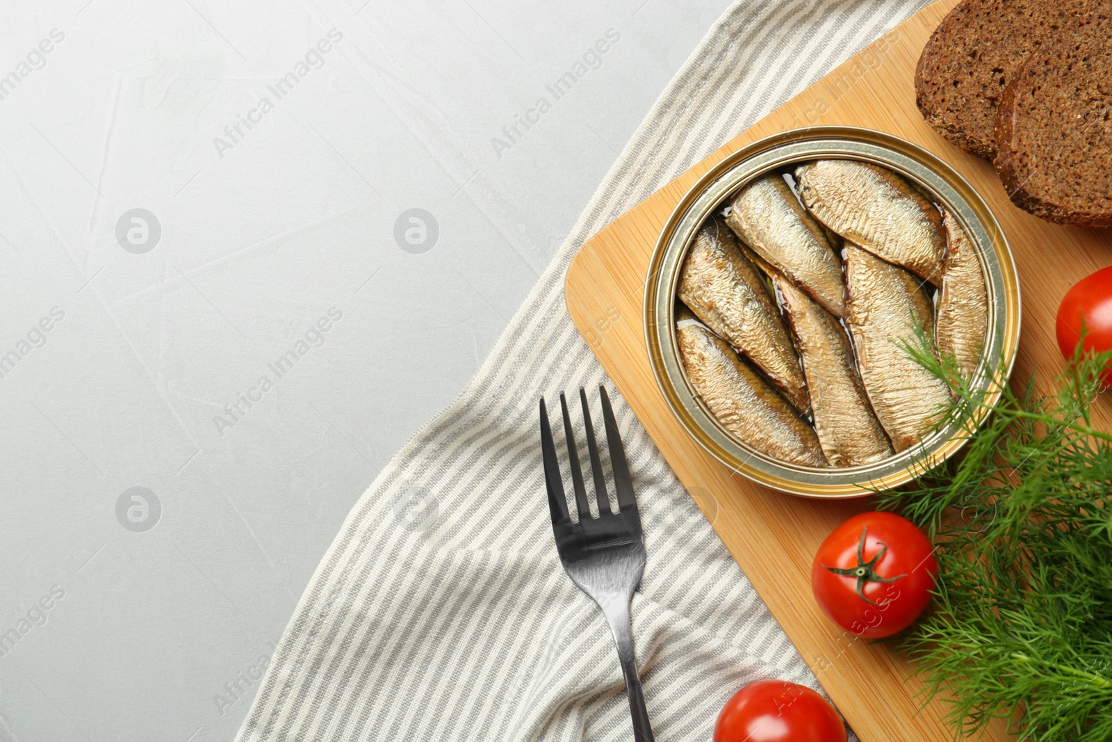 Photo of Canned sprats, dill, tomatoes, bread and fork on light table, flat lay. Space for text