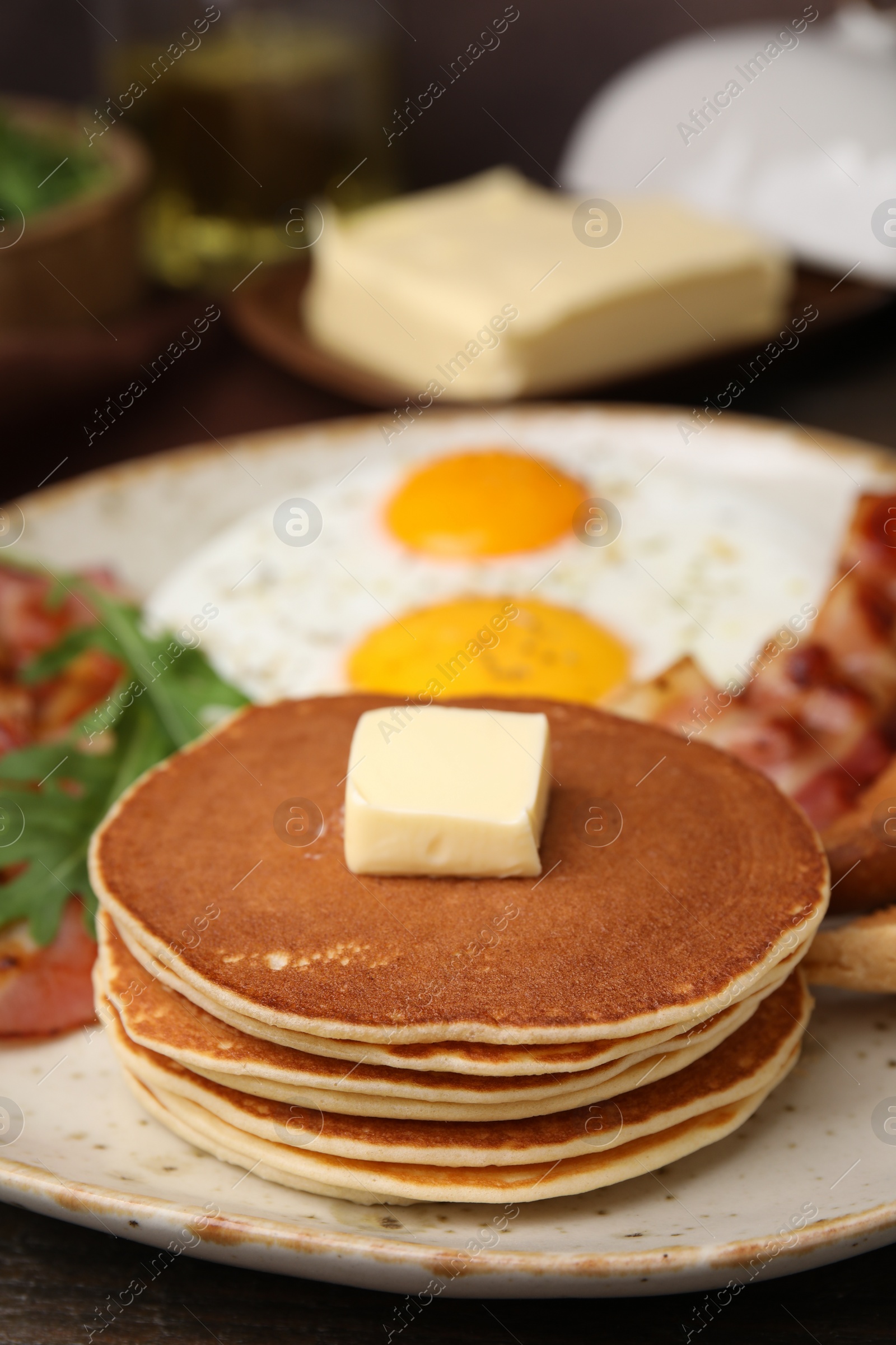 Photo of Tasty pancakes with fried eggs and bacon on wooden table, closeup