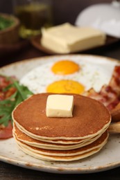 Photo of Tasty pancakes with fried eggs and bacon on wooden table, closeup