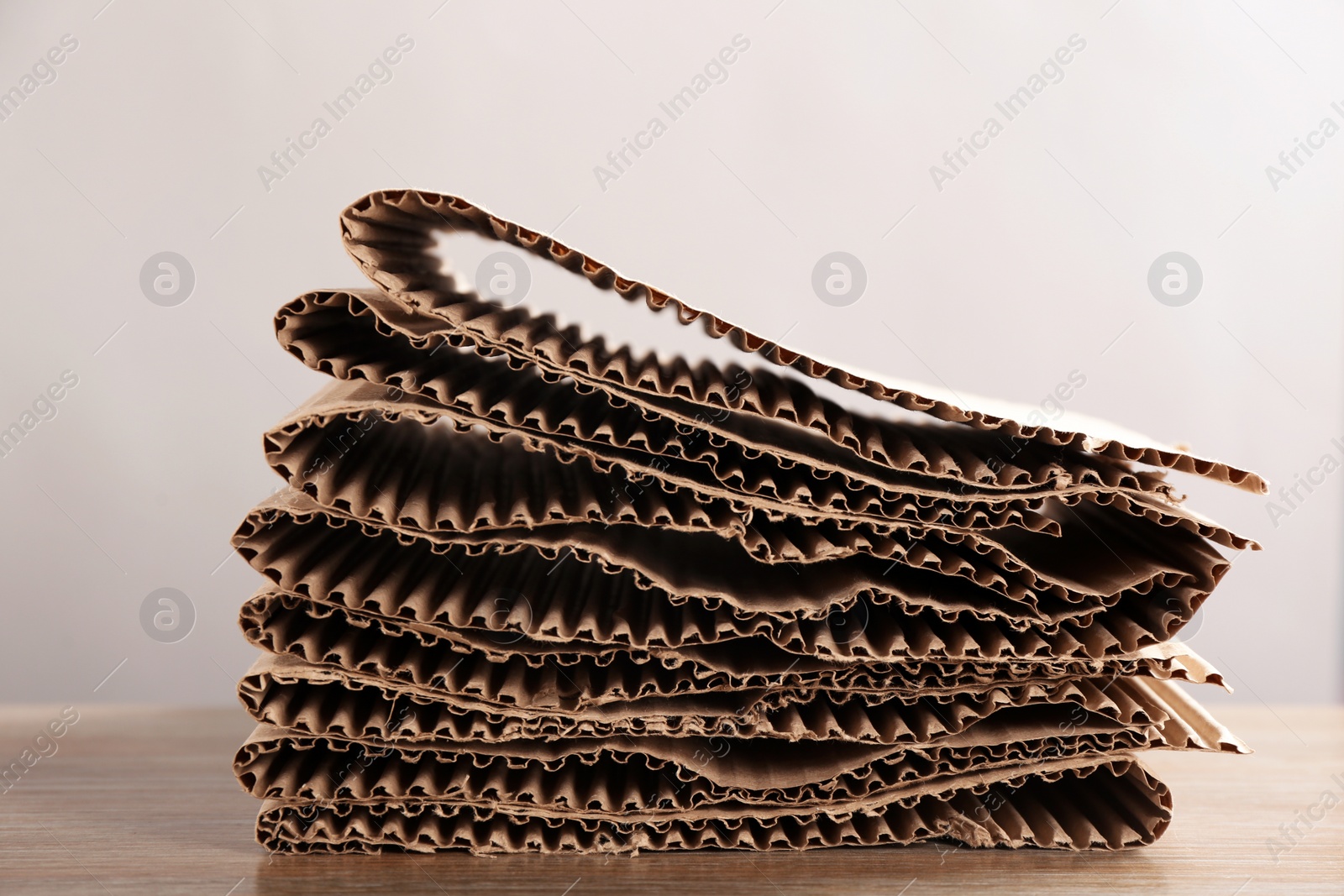 Photo of Stack of cardboard on table against light background, closeup. Recycling concept