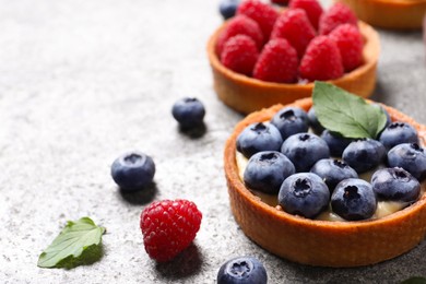 Photo of Tartlet with fresh blueberries on light grey table, closeup and space for text. Delicious dessert