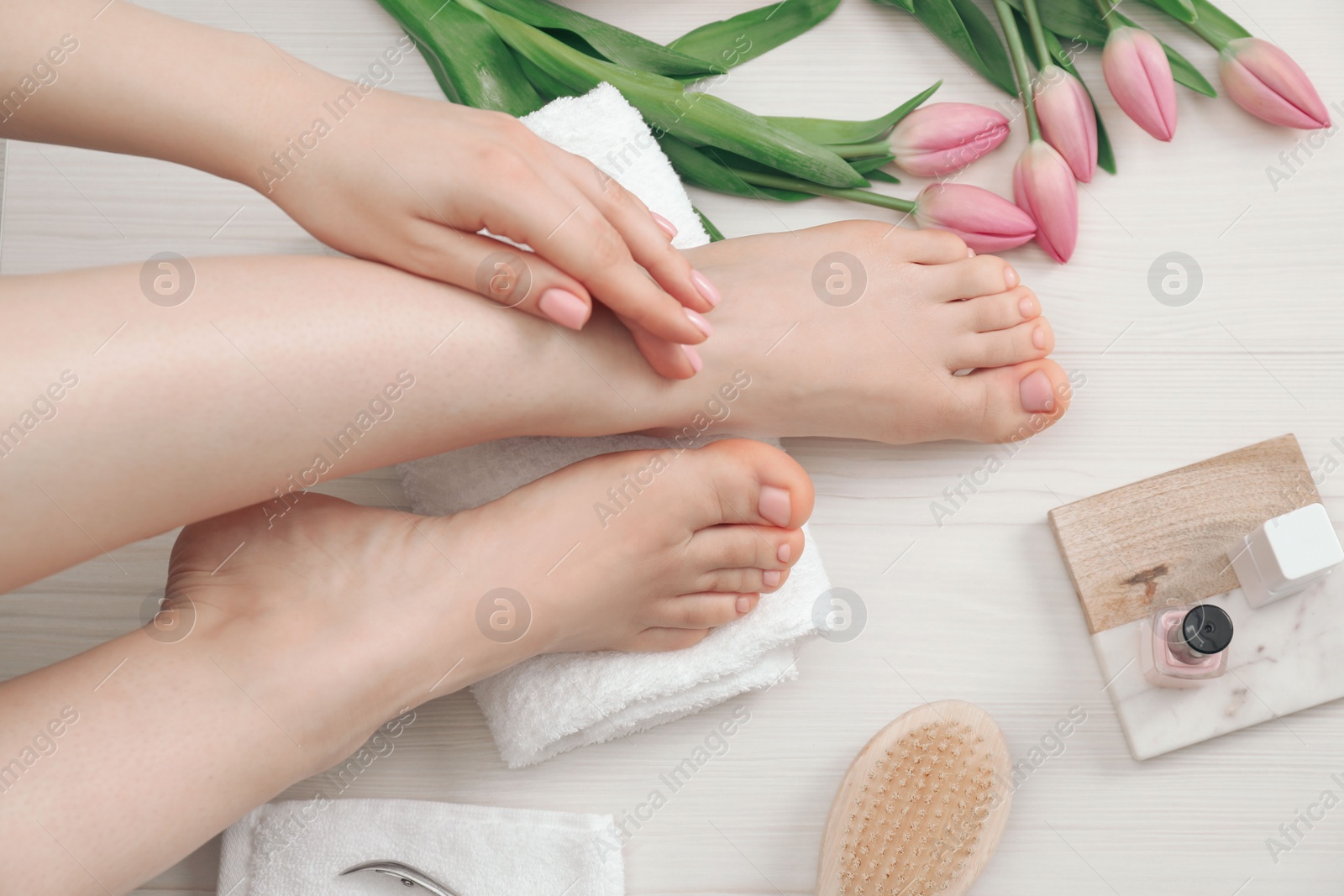 Photo of Woman with neat toenails after pedicure procedure on white wooden floor, top view